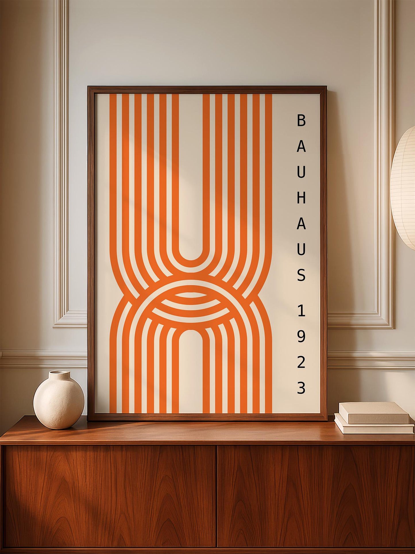a framed poster with a striking orange and white abstract design, displayed on a wooden cabinet or shelf.