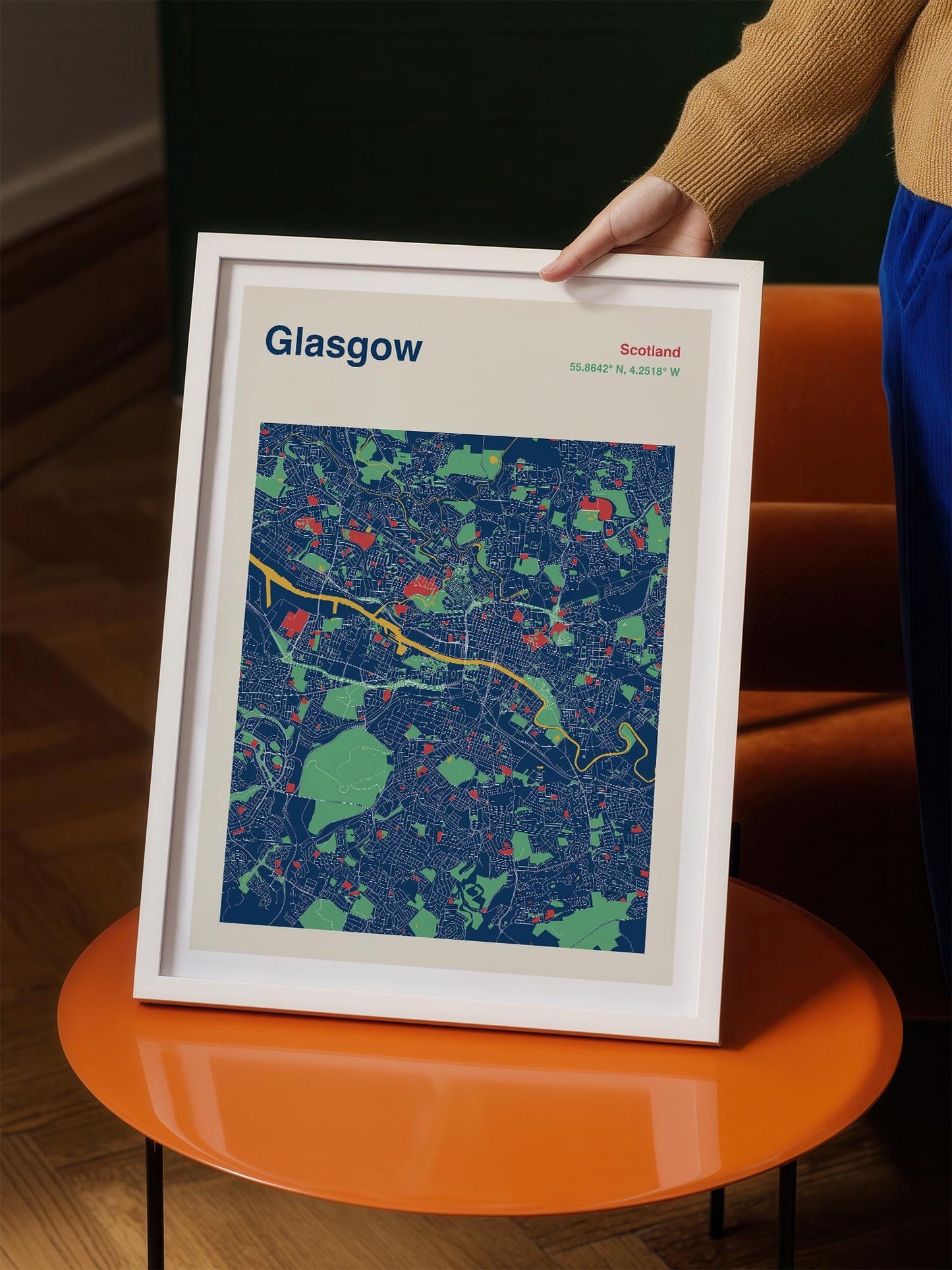 A person is holding a framed map of Glasgow, Scotland, which displays a colorful and detailed map of the city.
