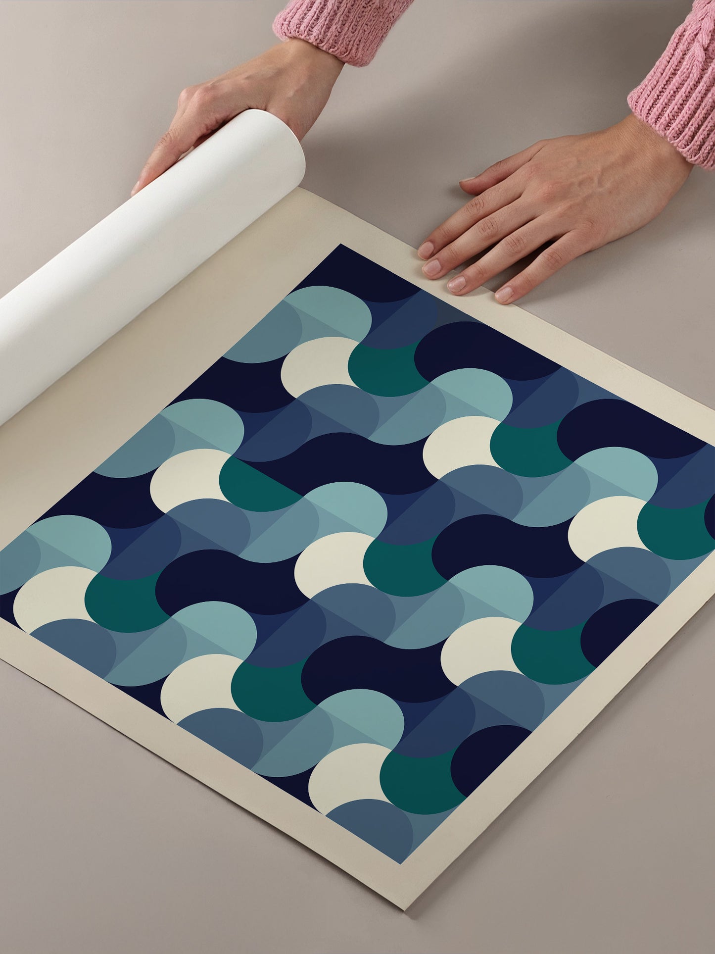 A person's hands are holding a roll of paper, which appears to be a piece of paper with a geometric pattern of overlapping circles in shades of blue and white.