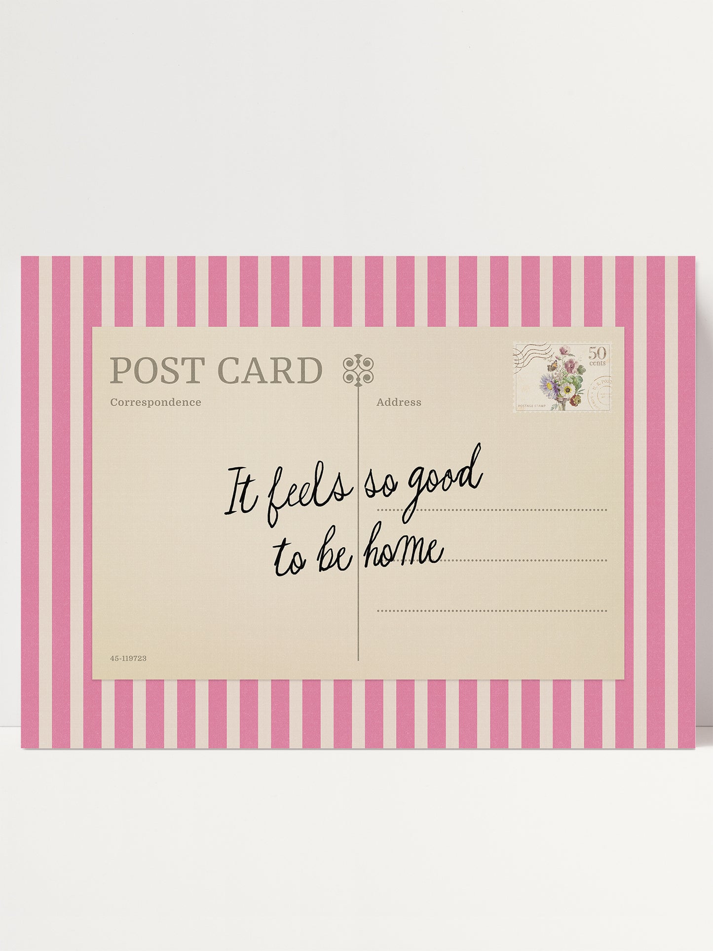 A pink and white striped postcard with a handwritten message that says "It feels so good to be home".