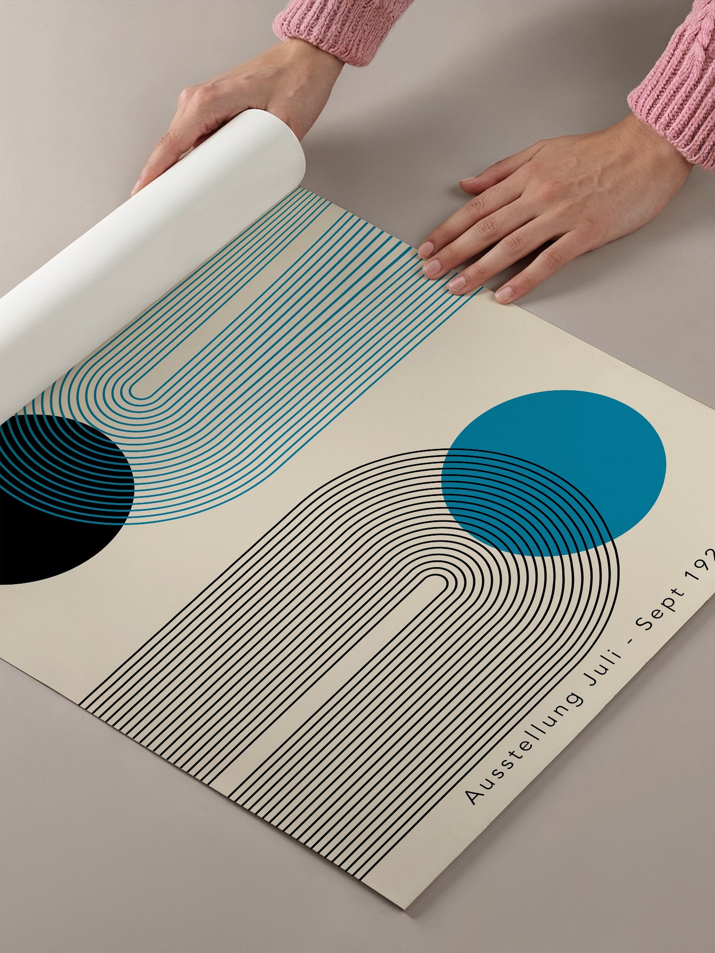A person's hands are holding a roll of paper with a geometric design featuring blue and black lines and circles.