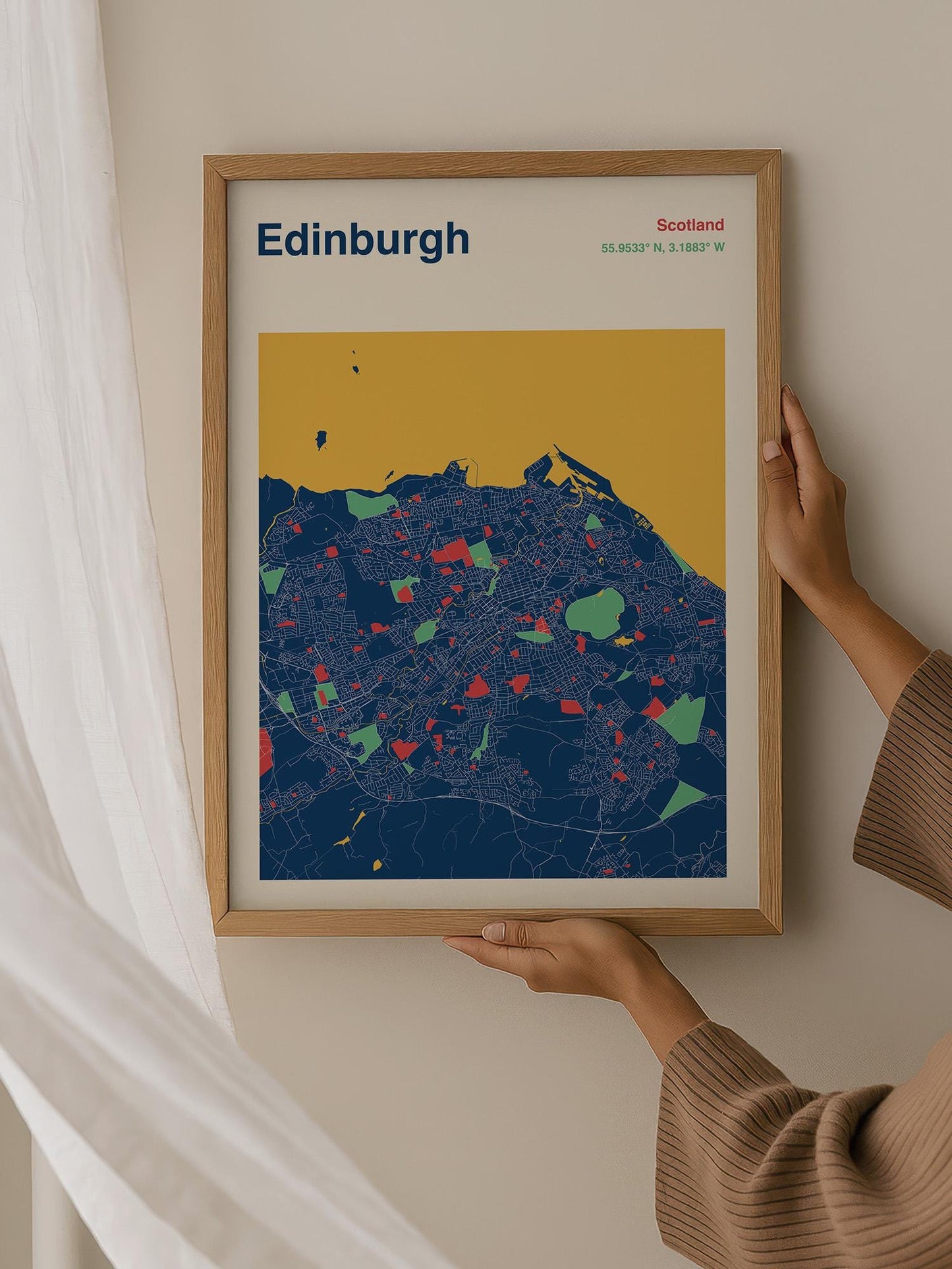 A person is holding up a framed map of Edinburgh, Scotland, which features a colorful and detailed representation of the city.