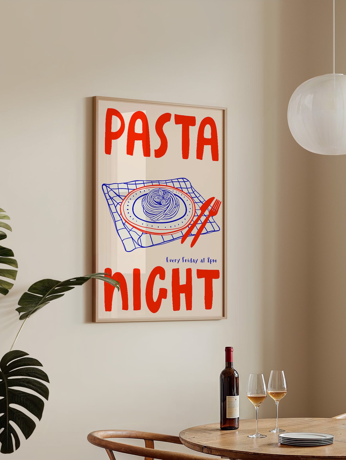 a framed poster with the text "PASTA NIGHT" and an illustration of a plate of spaghetti on a table. There is a bottle of wine and two glasses on the table, suggesting a dining setting.