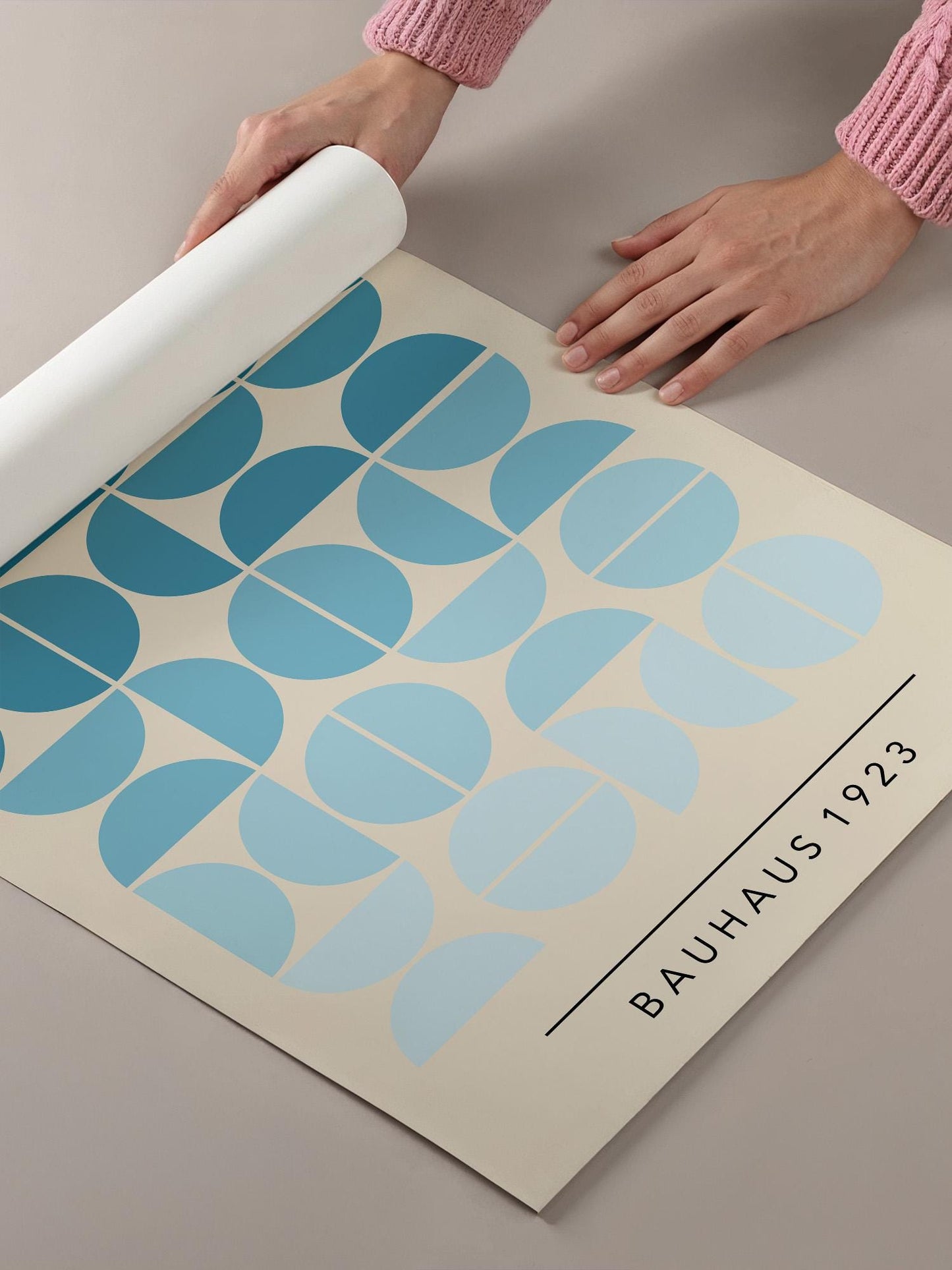 A person's hands are holding a roll of paper with a repeating pattern of blue and white circles, and the text "BAHAU'S 1923" is visible.