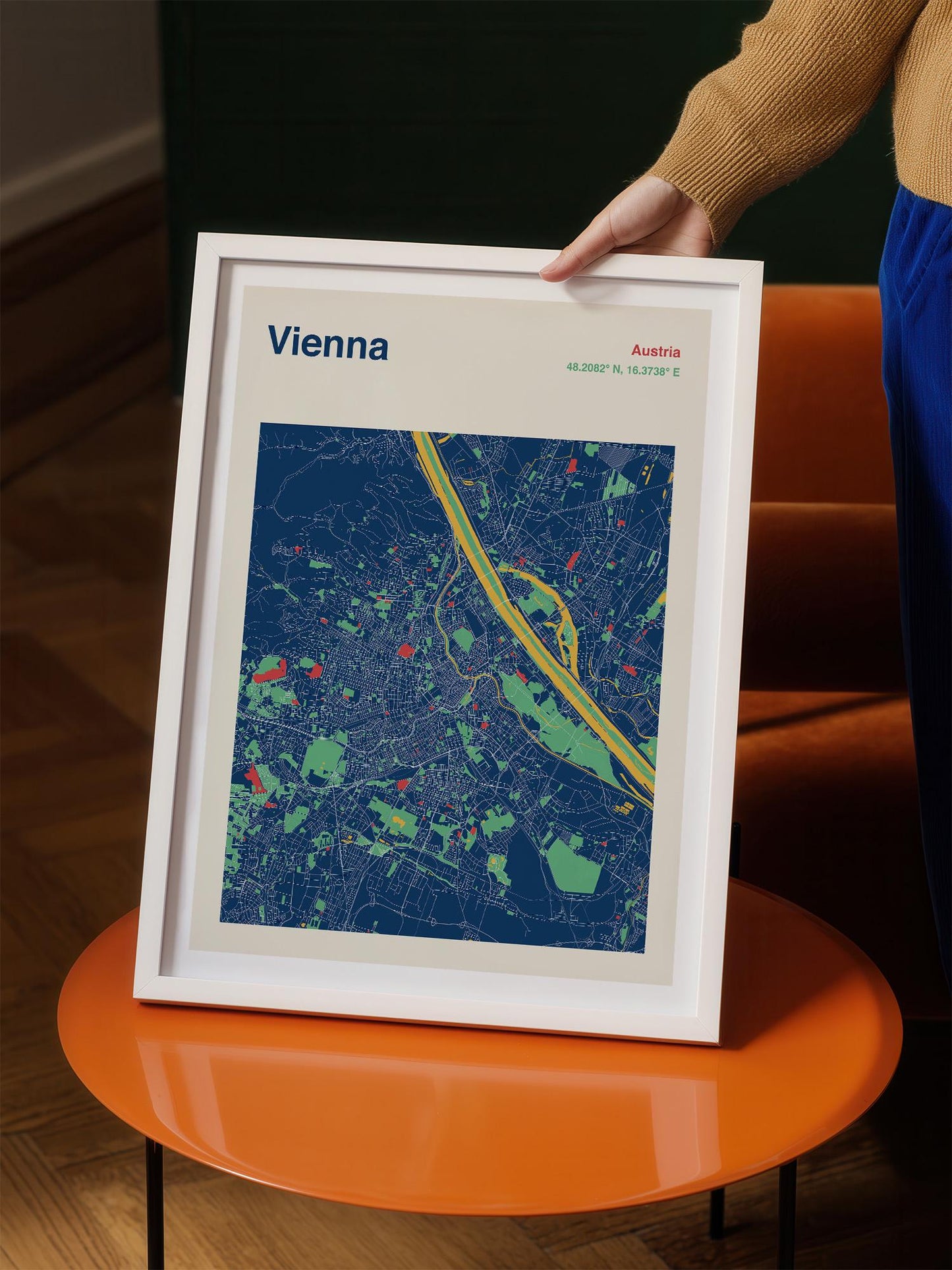 A person is holding a framed map of Vienna, Austria, which is a colorful and detailed representation of the city.