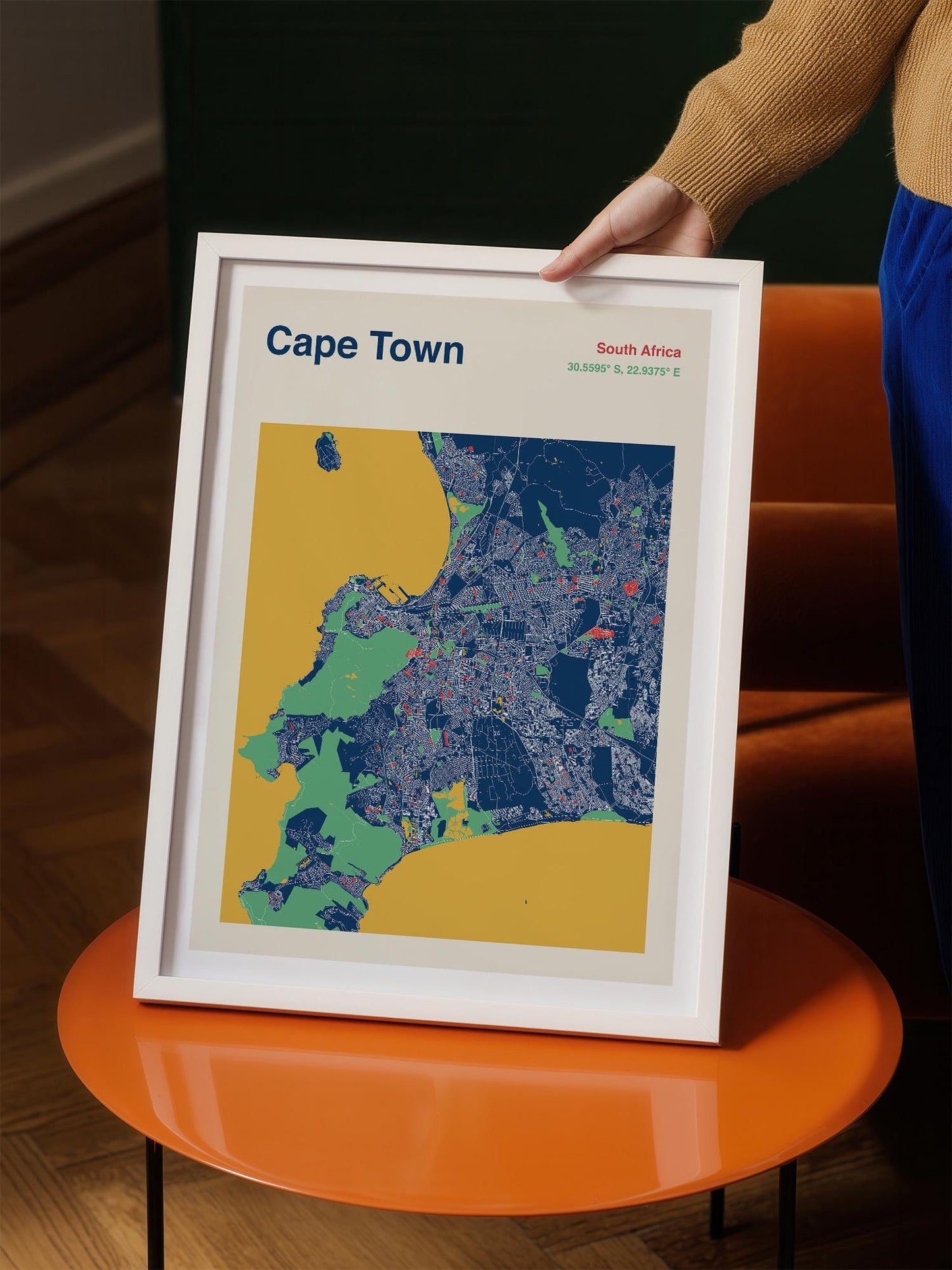 A person is holding a framed map of Cape Town, South Africa, which is a colorful and detailed representation of the city.