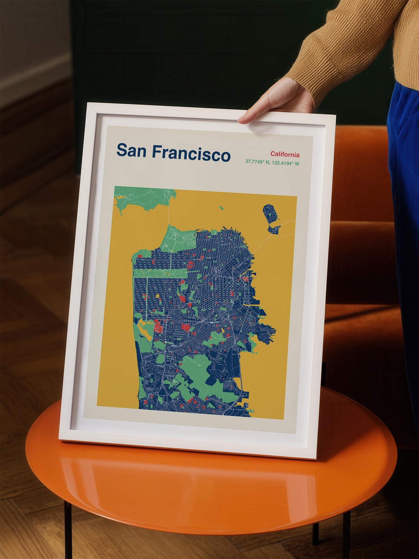 A person is holding a framed map of San Francisco, California, with a yellow background and a detailed illustration of the city's streets and neighborhoods.