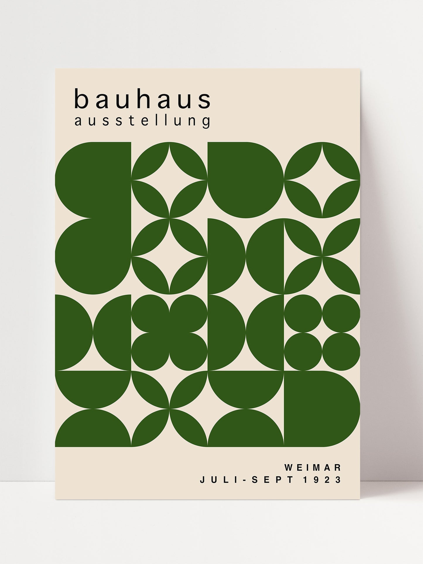 The image is a poster for the Bauhaus exhibition in Weimar, Germany, which took place from July to September 1923. The poster features a geometric design with green circles and shapes arranged in a repeating pattern.