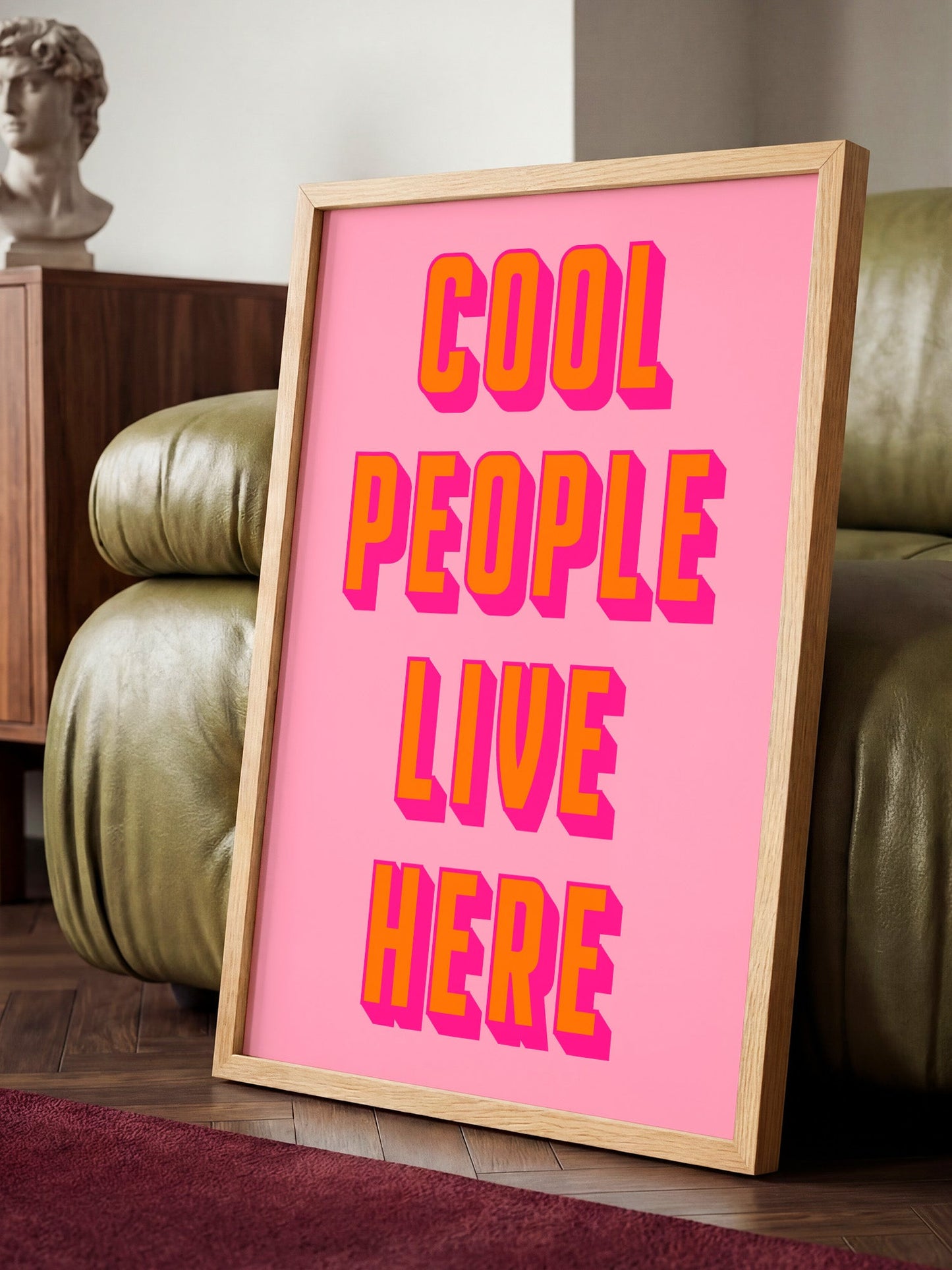 A framed poster with the text "COOL PEOPLE LIVE HERE" in large, bold letters against a pink background.