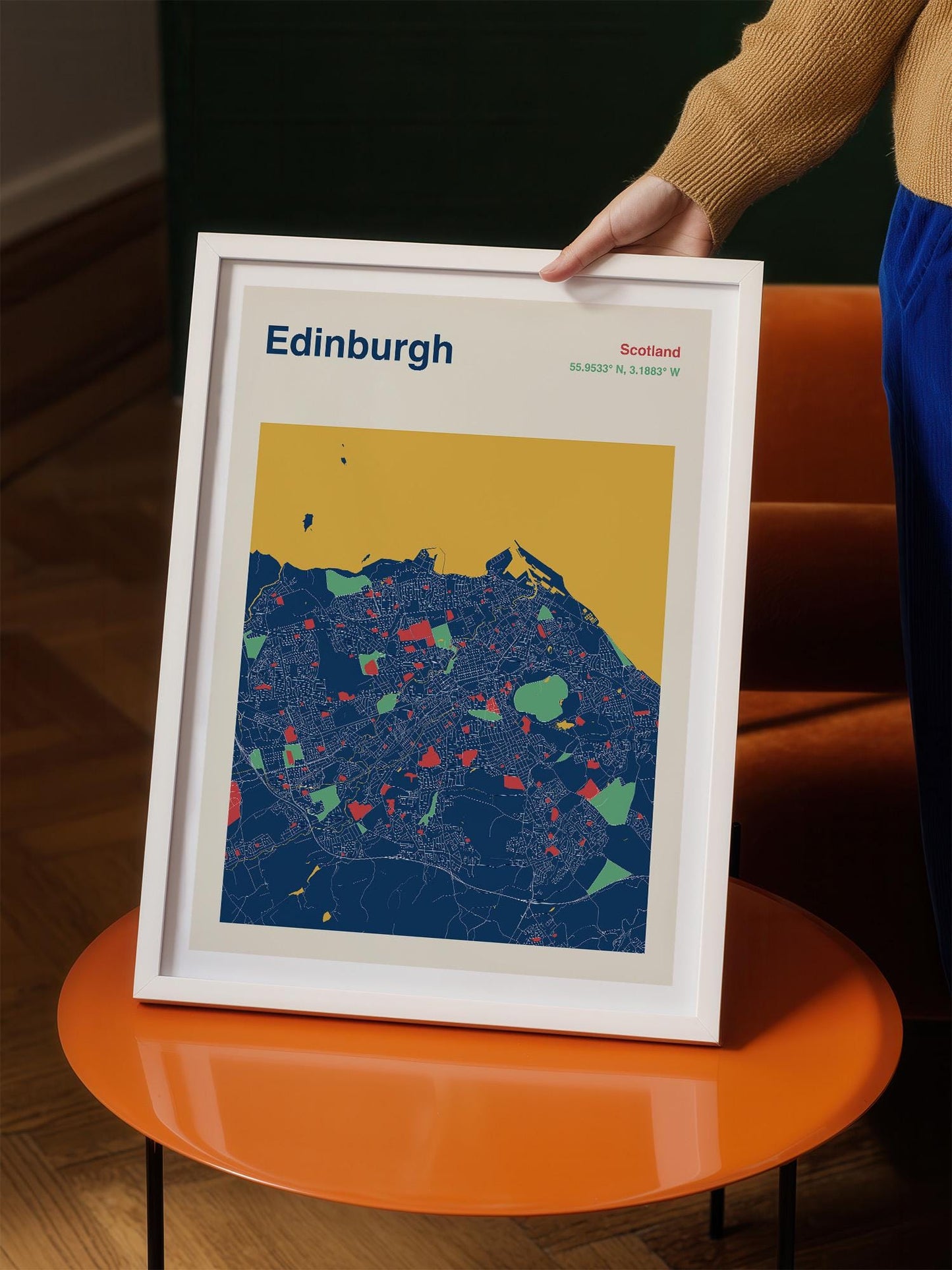 A person is holding a framed map of Edinburgh, Scotland, which features a colorful and detailed representation of the city.
