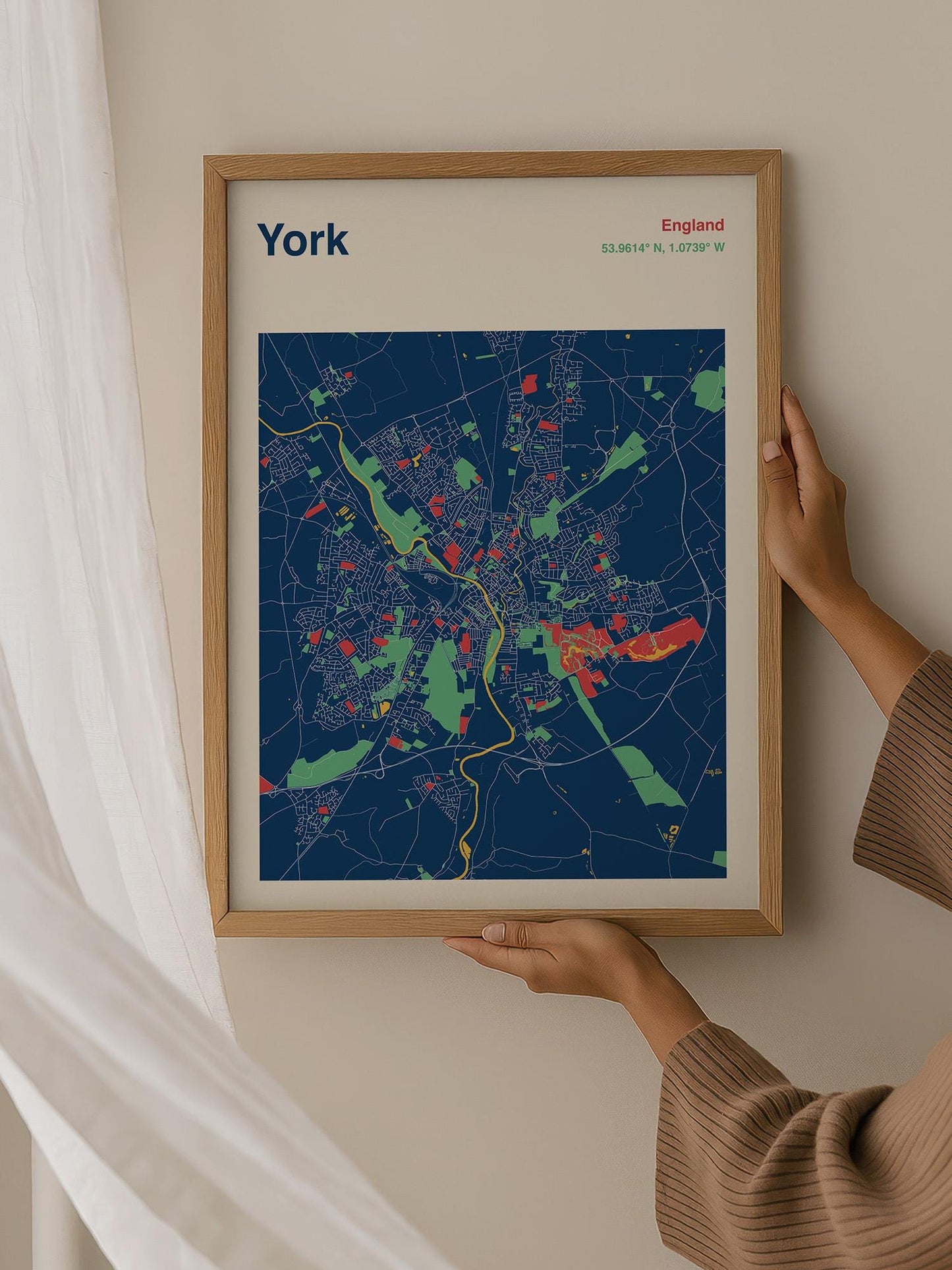 A person is holding up a framed map of York, England, which features a colorful and detailed representation of the city.