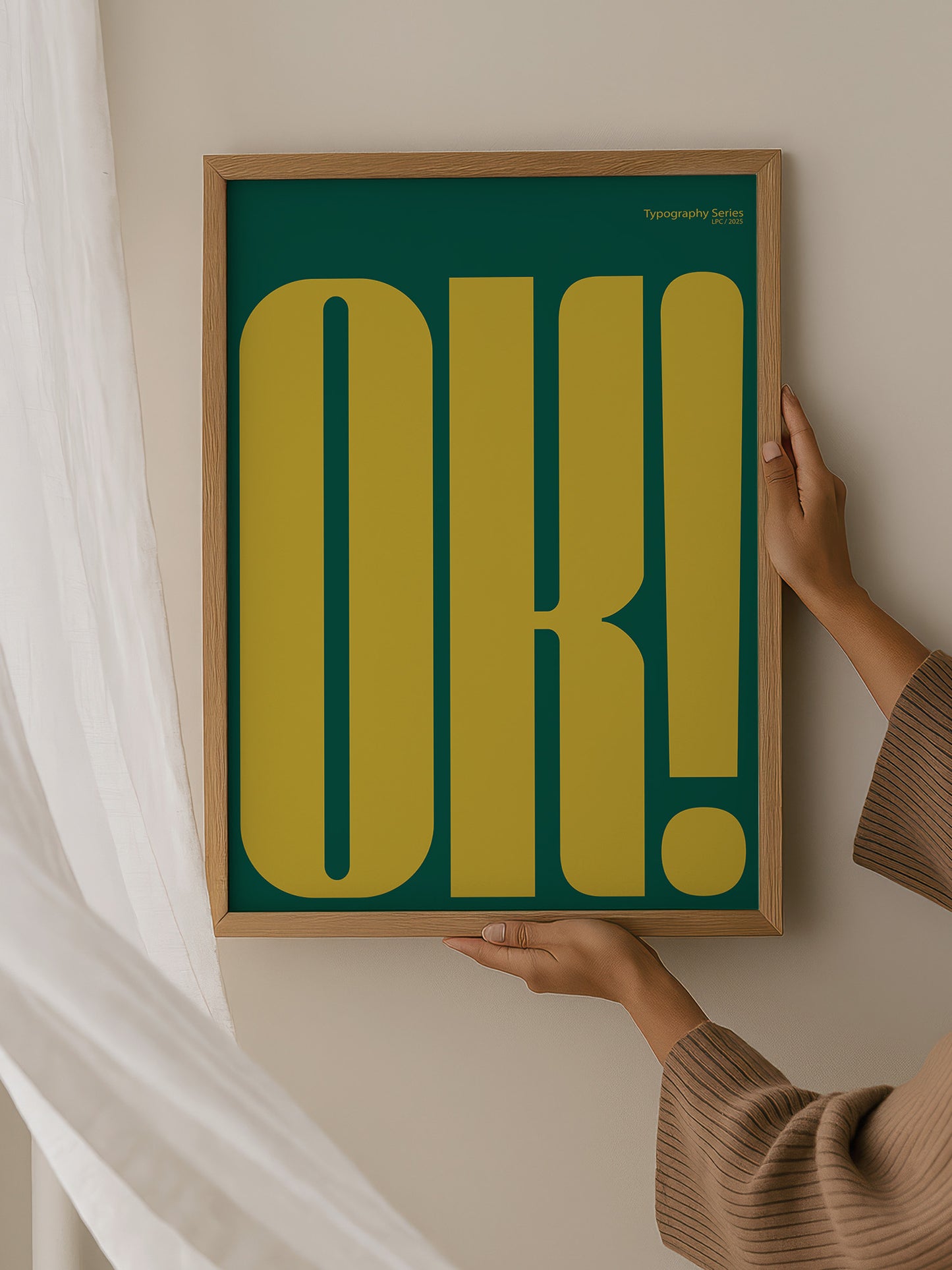 A person is holding up a framed poster with large yellow and green text that says "OK!"